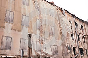 an evicted house under renovation half covered with material, outdoor shot photo