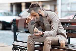 Eviction from home. Upset man sits on a bench outside with a miniature house. Loss of housing during the crisis, there is not