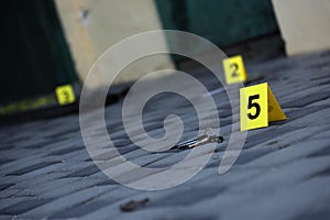 Evidence with yellow CSI marker for evidence numbering on the residental backyard in evening. Crime scene investigation concept