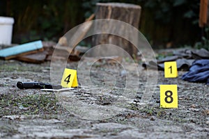 Evidence with yellow CSI marker for evidence numbering on the residental backyard in evening. Crime scene investigation concept