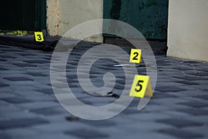 Evidence with yellow CSI marker for evidence numbering on the residental backyard in evening. Crime scene investigation concept