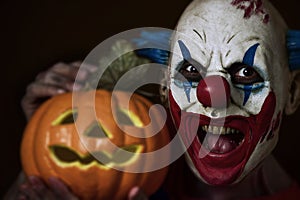 Evil clown with a carved pumpkin