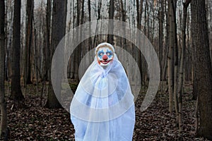 Evil clown in a dark forest in a white veil