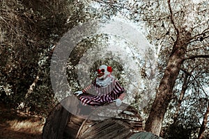 evil clown perched on a cable reel in the woods