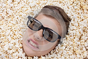 Evil ferocious young boy in stereo glasses looking out of popcorn