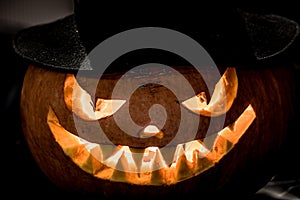 Evil Halloween pumpkin head in hat on a dark background