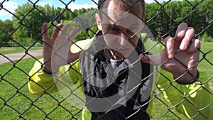 Evil Man in his 20s, leaning against the fence, trying to get out