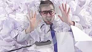 Evil man office worker in glasses cries in a large heaps of crumpled paper slow mo