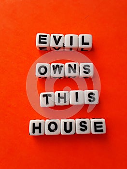 Evil owns this house words letters on white blocks on an orange background Halloween decoration