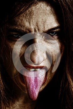 Evil scary sinister woman with tongue out photo