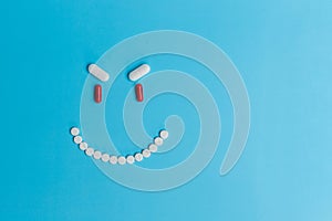 An evil smiling smiley face made of pills on a blue background