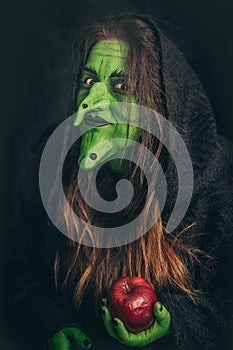 Evil witch holding a rotten apple