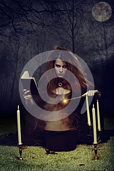 Witch at night using magic with wand