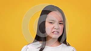 Eww. Cute little asian girl frowning her face, expressing disgust and aversion, smelling or tasting something awful