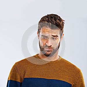 Eww. Studio shot of a young man frowning against a gray background.