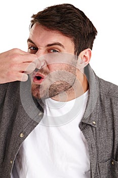 Ewwwww, that stinks. Closeup studio portrait of a young man holding his nose and suggesting an unpleasant smell.