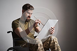 Ex-serviceman sitting in a wheelchair and painting a picture on a canvas