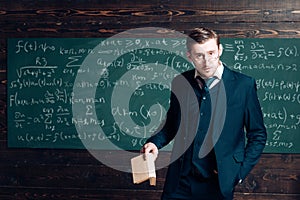 Exacting teacher. Teacher formal wear and glasses looks smart, chalkboard background. Man with high expectations looks