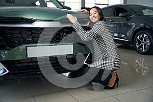 Exalted beautiful woman hugging a shining car hood