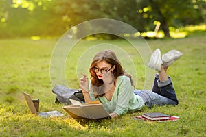Exam Study. Serious young student girl reading book outdoors in park