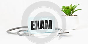 EXAM word on notebook,stethoscope and green plant