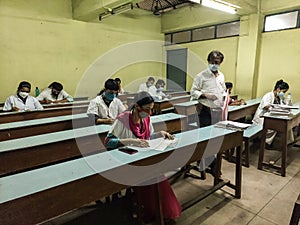 An examination hall with medical students and invigilator maintaining covid norms.
