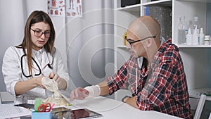 Examination of the patient in the doctor`s office with an injured wrist. The doctor examines an x-ray of the patient`s