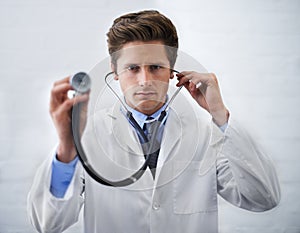 Examination time. a serious-looking doctor holding up the end of a stethoscope toward the camera.