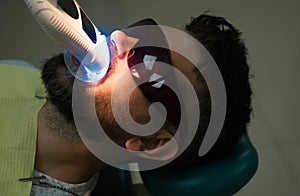 Examine of young man by dentist on light blurred background. Beautiful european man smile with healthy teeth whitening