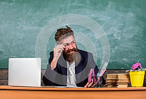 Examiner cunning face sit at table chalkboard background. School exam concept. He knew you cheated and he will proof it