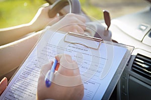 Examiner filling in driver`s license road test form