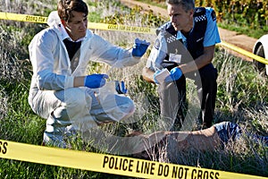 Examining the evidence. Shot of two investigators examining evidence at a crime scene.