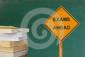 EXAMS AHEAD word on traffic sign with books and blackboard photo