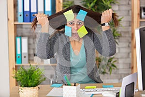 exasperated female employee covered in sticky reminder notes photo