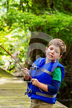 Exasperated Little Boy Looks at the Camera in Frustration Because His Fishing Pole is Caught in a Tree photo