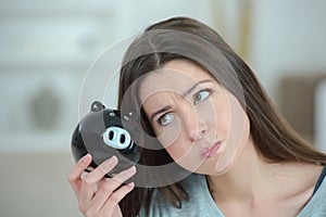 Exasperated woman holding piggy bank