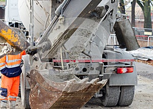 Exavator bucket filled with wet concrete to bring it to place of concrete works on building site