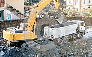 Exavator loading earth in the truck on construction site