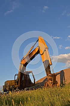 Excavating machine casts a shadow on sandpile