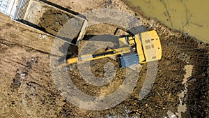 excavating soil into a dump truck to build a pond for store water for use in the dry season for agriculture, aerial top view
