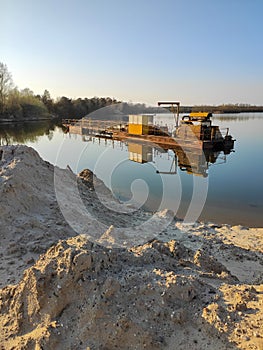 Excavation machine at earthmoving work in sand quarry. Extraction of sand from a lake.