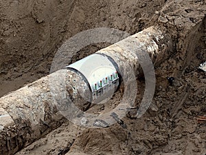 Excavation pit. Old drink water pipe with stainless repairing sleeve members.