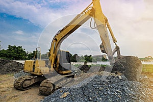 Excavation is working on the construction site at the sunset time in the summer season