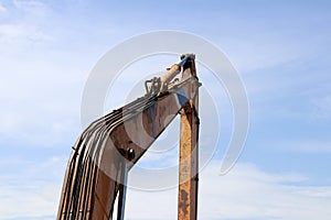 Excavator or backhoe bucket arm in yellow color on blue sky background.