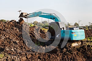 excavator backhoe working in the digging a soil to adjust the postharvest areas in the rice fields. agriculture machinery for