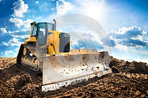Excavator with blue sky and sun in the background