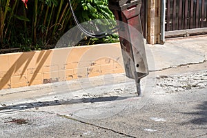 Excavator breaking and drilling the concrete road for repairing. Large pneumatic hammer mounted on the hydraulic arm of a construc