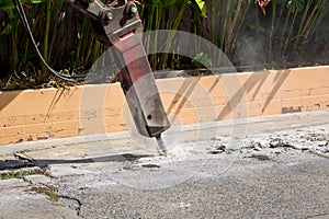 Excavator breaking and drilling the concrete road for repairing. Large pneumatic hammer mounted on the hydraulic arm of a construc