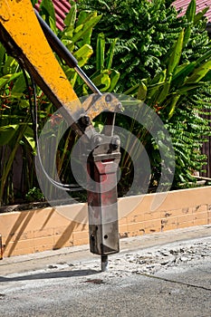 Excavator breaking and drilling the concrete road for repairing. Large pneumatic hammer mounted on the hydraulic arm of a construc