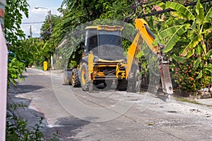 Excavator breaking and drilling the concrete road for repairing. Large pneumatic hammer mounted on the hydraulic arm of a construc